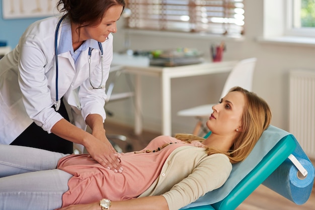 Doctor examining a patient's abdomen during a consultation