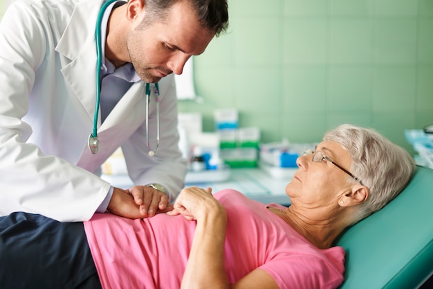 Doctor gently examining the abdomen of an elderly patient